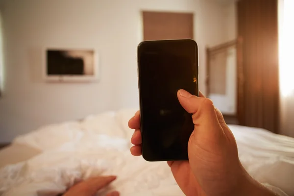 Persona en la cama mirando el teléfono móvil —  Fotos de Stock