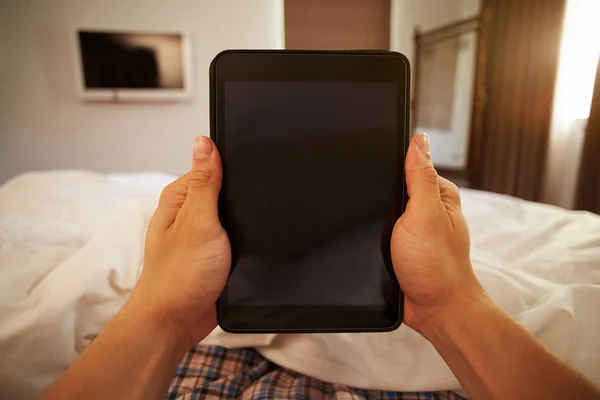 Mann i sengen ser på digitale nettbrett – stockfoto