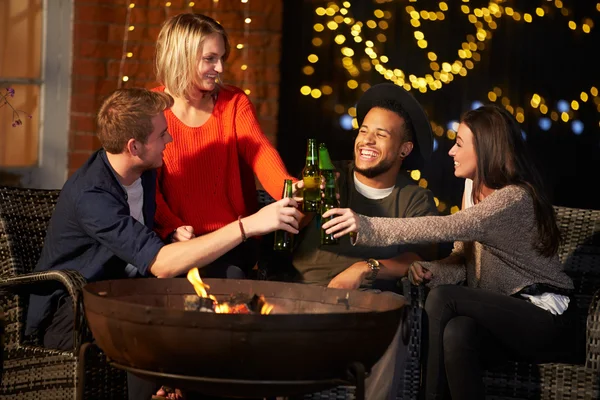 Amigos desfrutando de bebidas noturnas por Firepit — Fotografia de Stock