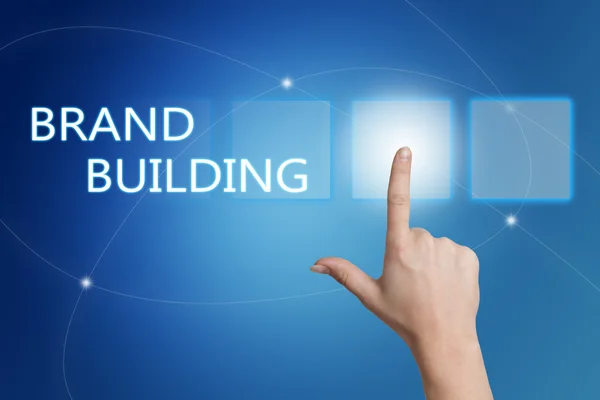 Brand Building - bouton-poussoir main sur l'interface avec fond bleu . — Photo