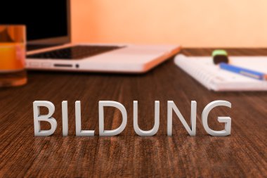 Bildung - german word for education - letters on wooden desk with laptop computer and a notebook. 3d render illustration.