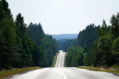 Yol ufkun ötesine doğru uzanır tepelerden ormana doğru. Bakış açısı. Sıcak güneşli yaz                              
