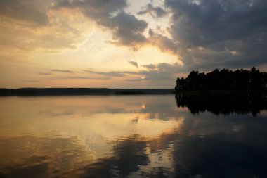 Temmuz 'da yaz akşamı. Sıcak bir günün ardından gölün üzerinde gün batımı. Sessiz cazibe ve yansıma. Ufuk                               