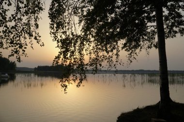  Temmuz 'da yazın gölde akşam yemeği. Sazlıklar suyun sakin yüzeyine yansıyor. Yumuşak ve parlak renkler. Günbatımı ve Silutes                              