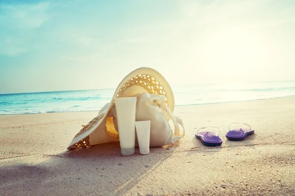 Lozione solare, cappello con borsa sulla spiaggia tropicale — Foto Stock