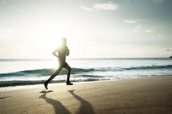 Seorang pria berlari di pantai tropis saat matahari terbenam — Stok Foto