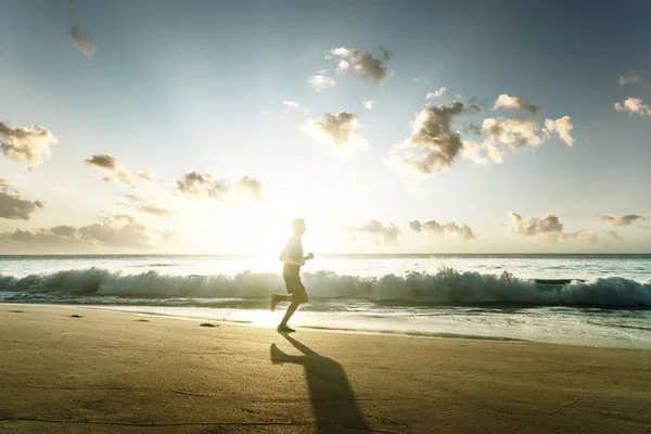 Man som springer på tropisk strand vid solnedgången — Stockfoto