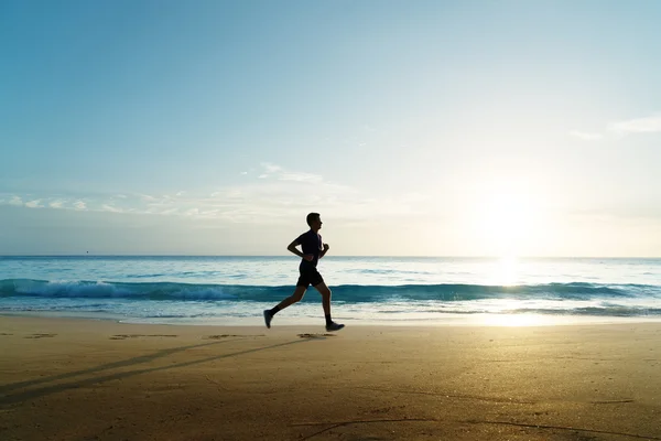 Uomo che corre sulla spiaggia tropicale al tramonto — Foto Stock