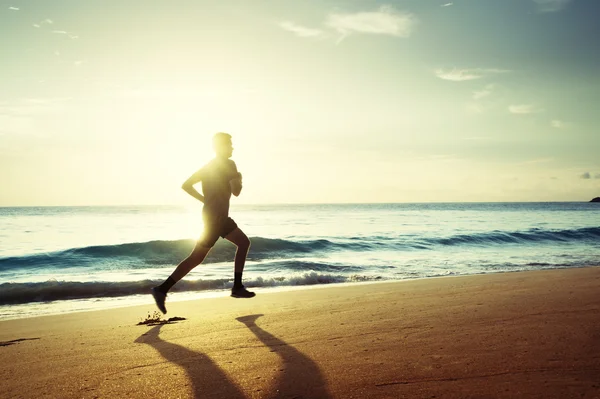 Homme courant sur la plage tropicale au coucher du soleil — Photo