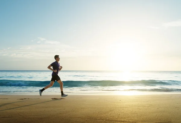 Homme courant sur la plage tropicale au coucher du soleil — Photo