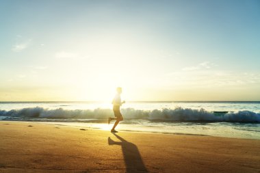 Günbatımında tropik plajda koşan bir adam