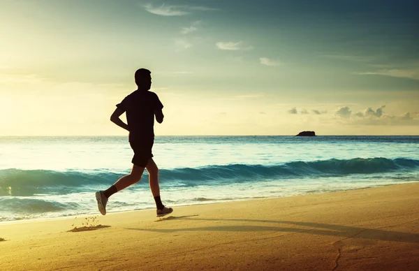 Uomo che corre sulla spiaggia tropicale al tramonto — Foto Stock