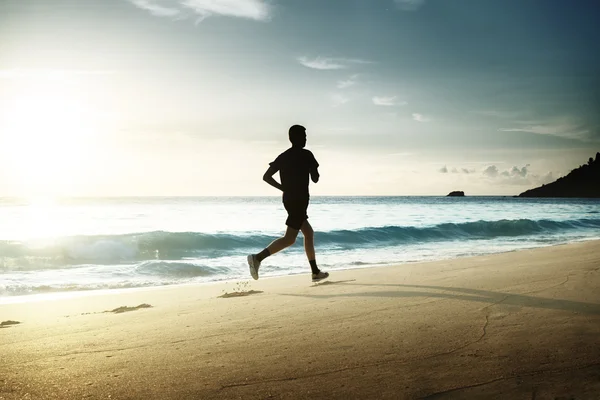 Homme courant sur la plage tropicale au coucher du soleil — Photo