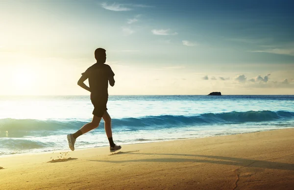 Uomo che corre sulla spiaggia tropicale al tramonto — Foto Stock