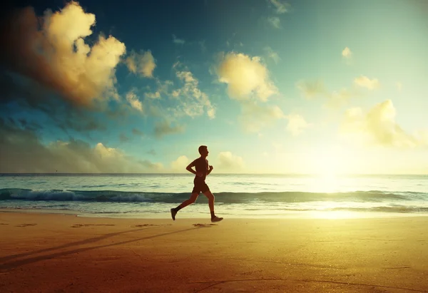 Man som springer på tropisk strand vid solnedgången — Stockfoto