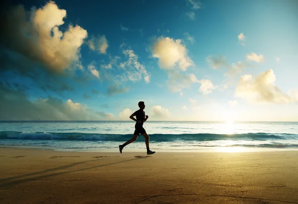 Homme courant sur la plage tropicale au coucher du soleil — Photo