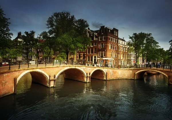 Amsterdamse grachten met brug en typische huizen, Nederland — Stockfoto