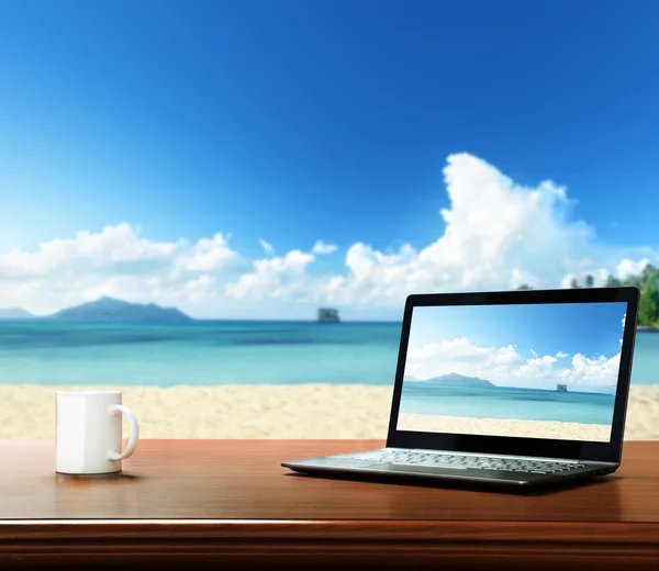 Ноутбук на столе и тропическом пляже — стоковое фото