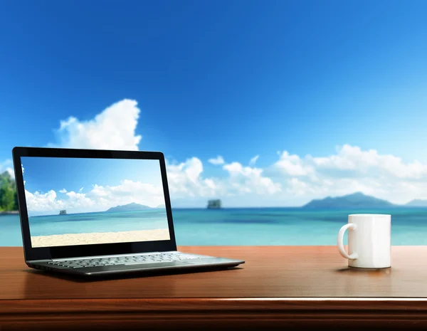 Portátil sobre mesa y playa tropical — Foto de Stock