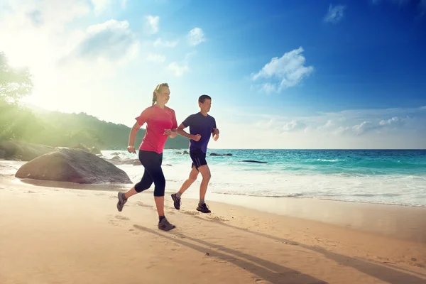 Hombre y mujer corriendo en la playa tropical al atardecer — Foto de Stock