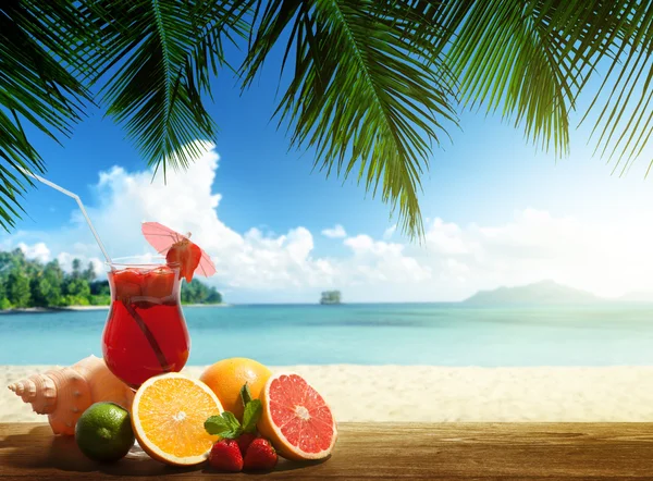 Strawberry cocktail and tropical fruit on the beach — Stock Photo, Image