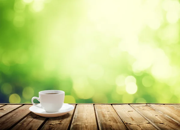 Cup coffee and sunny trees background — Stock Photo, Image