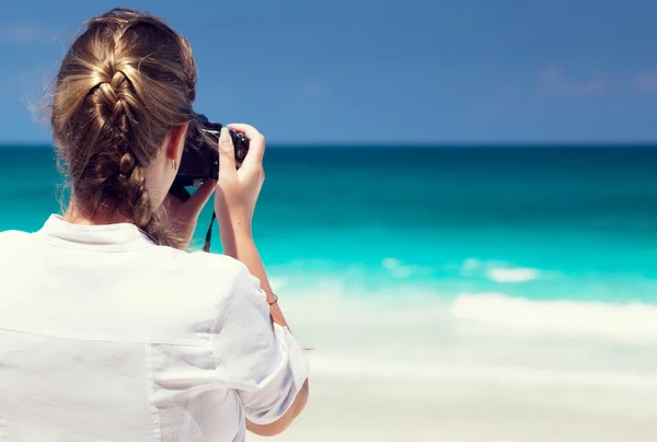 Mujer en la playa tropical tomando fotos con cámara sin espejo —  Fotos de Stock