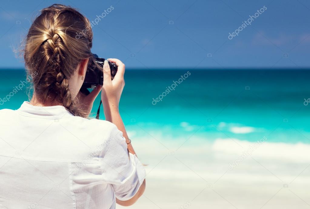 woman on tropical beach taking photo with mirrorless camera