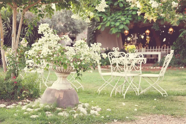 Witte tafel en stoelen in de prachtige tuin. Vintage stijl prentbriefkaar — Stockfoto