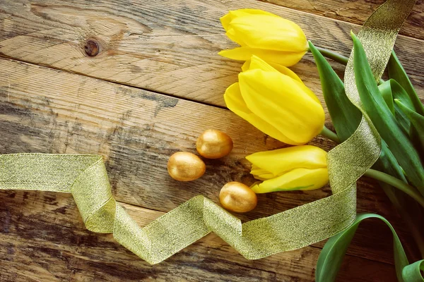 Fond pascal avec tulipes, trois œufs dorés — Photo