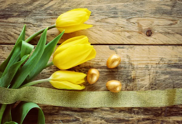 Fond pascal avec tulipes, trois œufs dorés — Photo