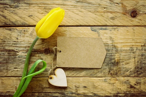 Etiqueta amarilla de tulipán y papel en mesa de madera —  Fotos de Stock