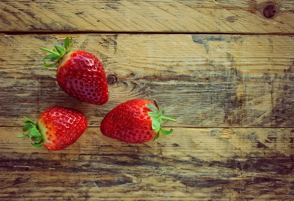 Drei Erdbeeren auf Holztisch — Stockfoto