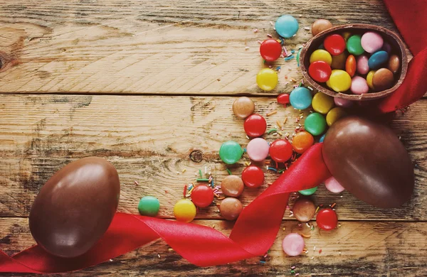 Ovos de chocolate de Páscoa, doces multicoloridos, fita vermelha — Fotografia de Stock