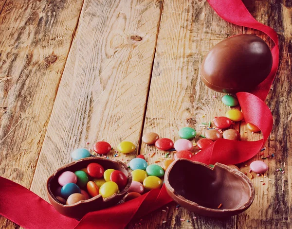 Huevos de chocolate de Pascua, dulces multicolores, cinta de seda roja — Foto de Stock