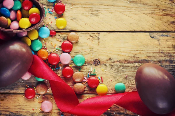 Пасхальные шоколадные яйца, конфеты, красная лента — стоковое фото