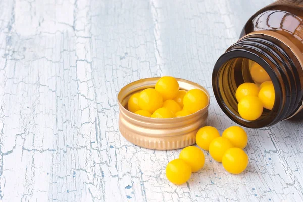Garrafa de vidro com vitaminas amarelas pílulas — Fotografia de Stock