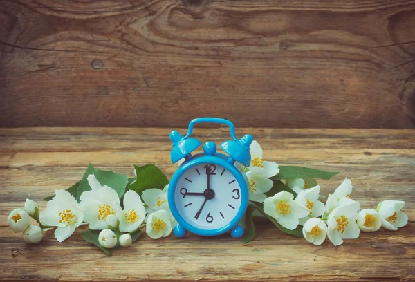 Blue alarm clock, jasmine branches — Stock Photo, Image