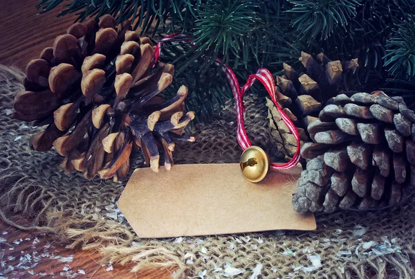 Рождественский фон с шишками, золотой колокольчик — стоковое фото