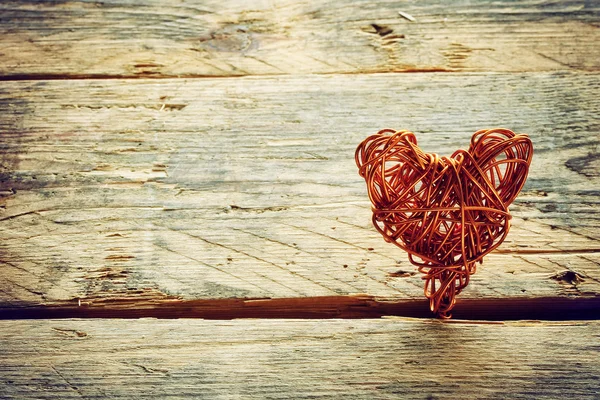 Braided wire heart on old wooden planks — Stock Photo, Image