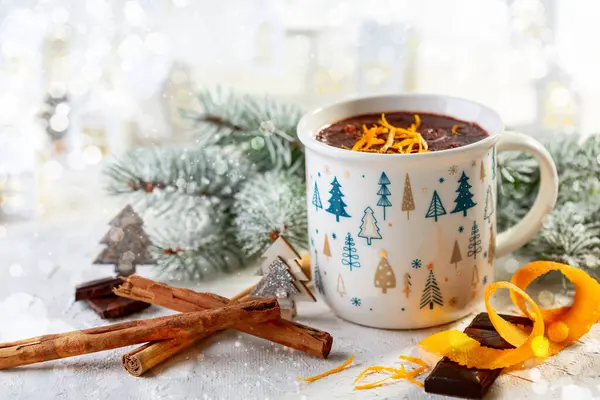 Cozy winter composition with a cup of hot chocolate and snow-covered branches on a bright festive background. Christmas or winter drink concept.