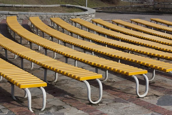 Rij met gele houten zitplaatsen — Stockfoto