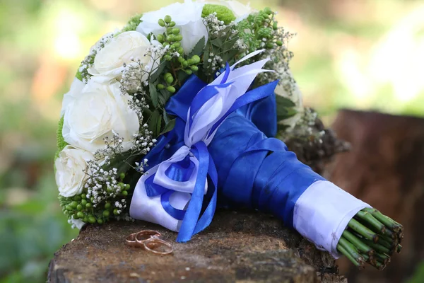 Wedding rings and wedding bouquet on wood — Stock Photo, Image