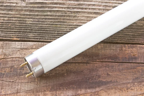 Флуоресцентная светло-белая трубка на деревянном фоне — стоковое фото