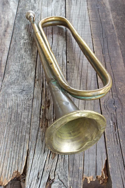 Old broken army trumpet on wooden background — Stock Photo, Image