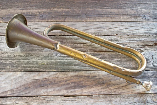 Old broken army trumpet on wooden background Royalty Free Stock Images