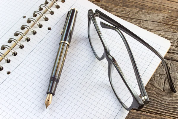 Fountain pen and spiral notebook with eyeglasses — Stock Photo, Image