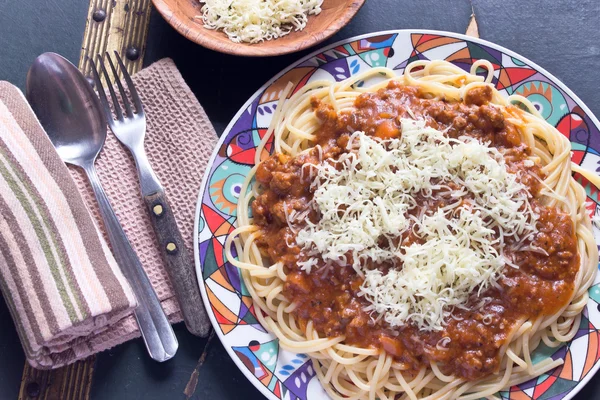 Spaghetti bolognese on plate with fork and spoon on table — Stock Photo, Image