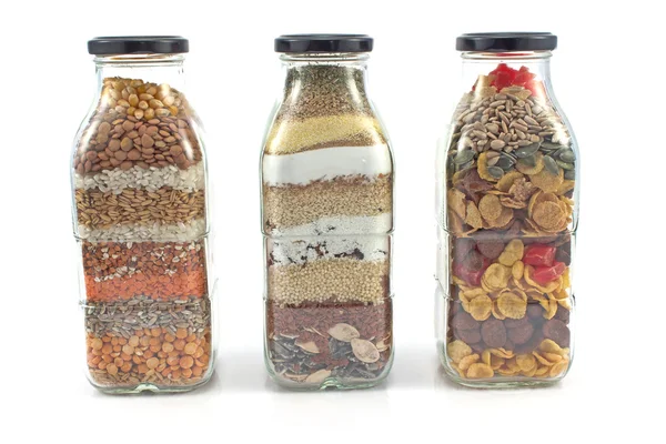 Decorative glass bottles with seeds isolated on white — Stock Photo, Image