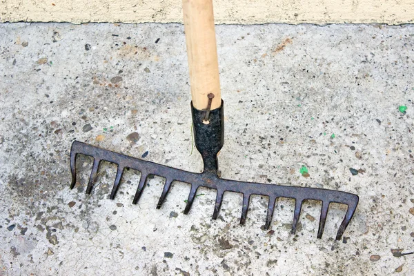 Ferramenta ancinho sobre fundo de concreto — Fotografia de Stock